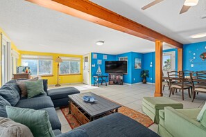 A living room with a sofa set, a coffee table, a TV, and a dining area with chairs.