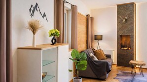 A modern living room with a sofa, a fireplace, a small table, and a plant.