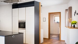 A modern kitchen with a built-in oven, a black and white cabinet, and a wooden floor.