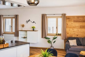 Une cuisine moderne avec des meubles blancs, un plan de travail en bois et un coin repas comprenant une table et des chaises.