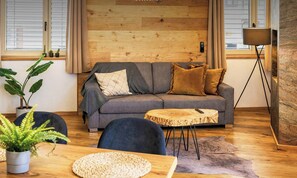 A modern living room with a grey sofa, a round wooden coffee table, and a potted plant.