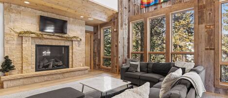 A spacious living room with a stone fireplace, large windows, and a modern sofa set.