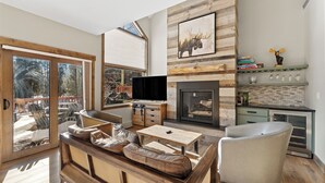 Un salon moderne avec une cheminée, un téléviseur et un coin repas.