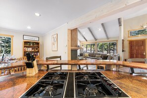 Una cocina amplia con una isla central, vigas de madera y un ventanal con vistas a un jardín.