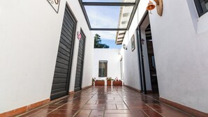 Un pasillo estrecho con techo de vidrio, paredes blancas y piso de baldosas.