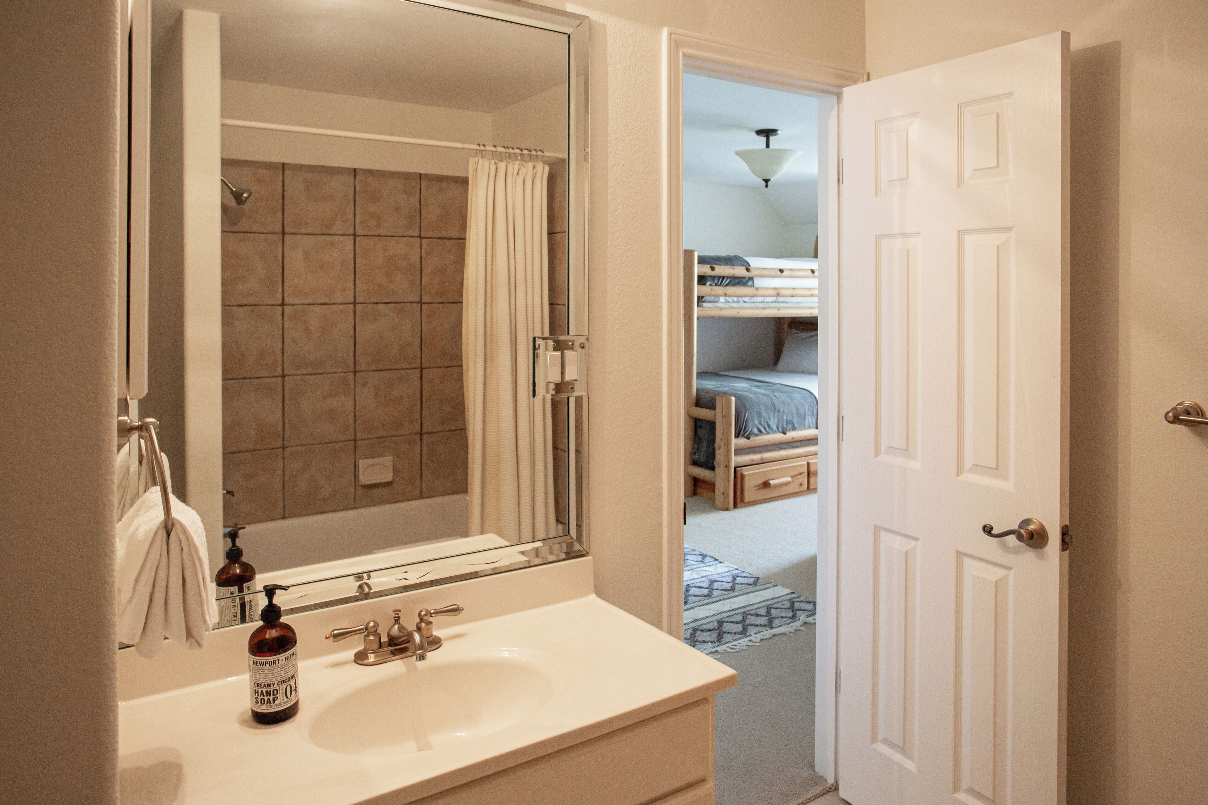 A bathroom with a sink, mirror, and shower.