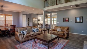 A spacious living room with leather sofas, a wooden coffee table, and a patterned rug. - Lakefront 6BR Retreat w Dock & Game Room (Burnet)