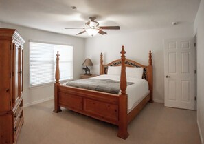 A bedroom with a four-poster bed, a ceiling fan, a nightstand with a lamp, and a dresser. - Lakefront 6BR Retreat w Dock & Game Room (Burnet)