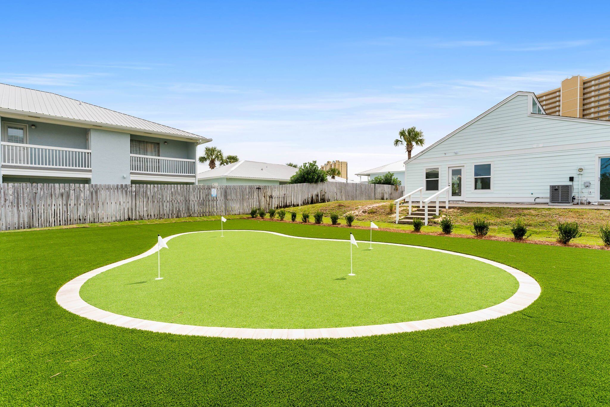 A golf course with a white fence, a wooden deck, and a building with a white exterior.