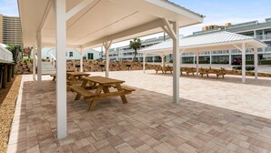Un patio al aire libre con mesas de picnic y zonas de estar cubiertas.