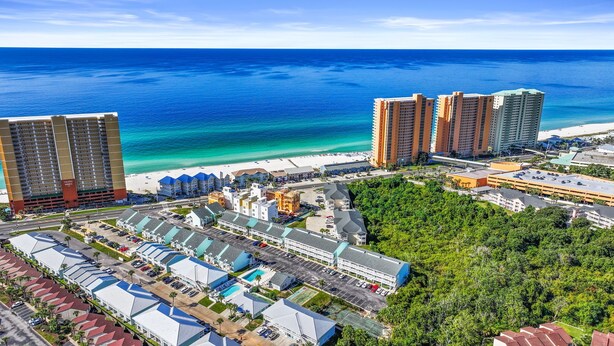 Un hotel frente al mar con varios edificios altos, una playa y un estacionamiento.