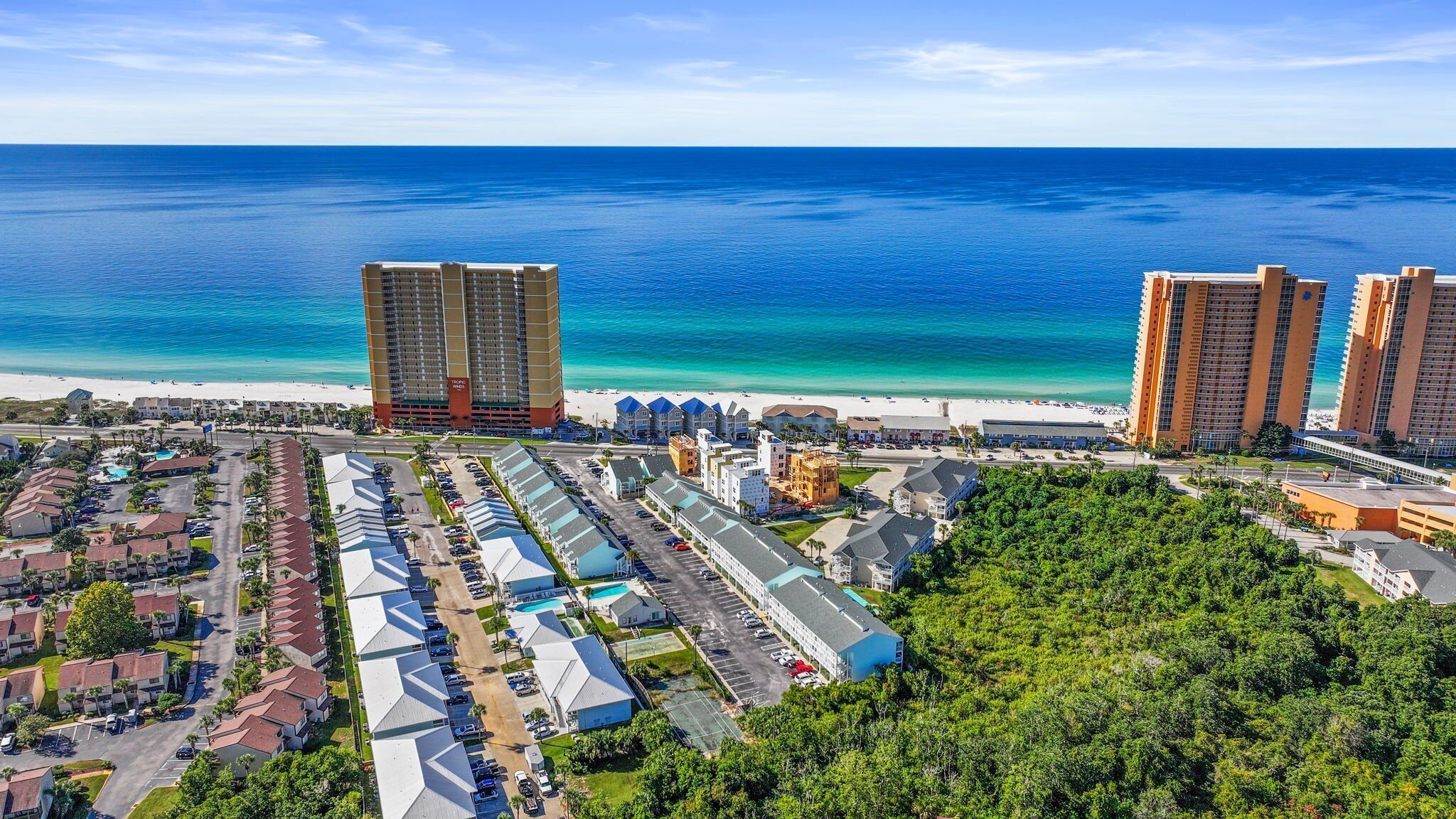 Zona hotelera costera con varios edificios de gran altura, una playa y un estacionamiento.