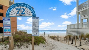 Un letrero de acceso a la playa con normas y advertencia sobre socorristas.