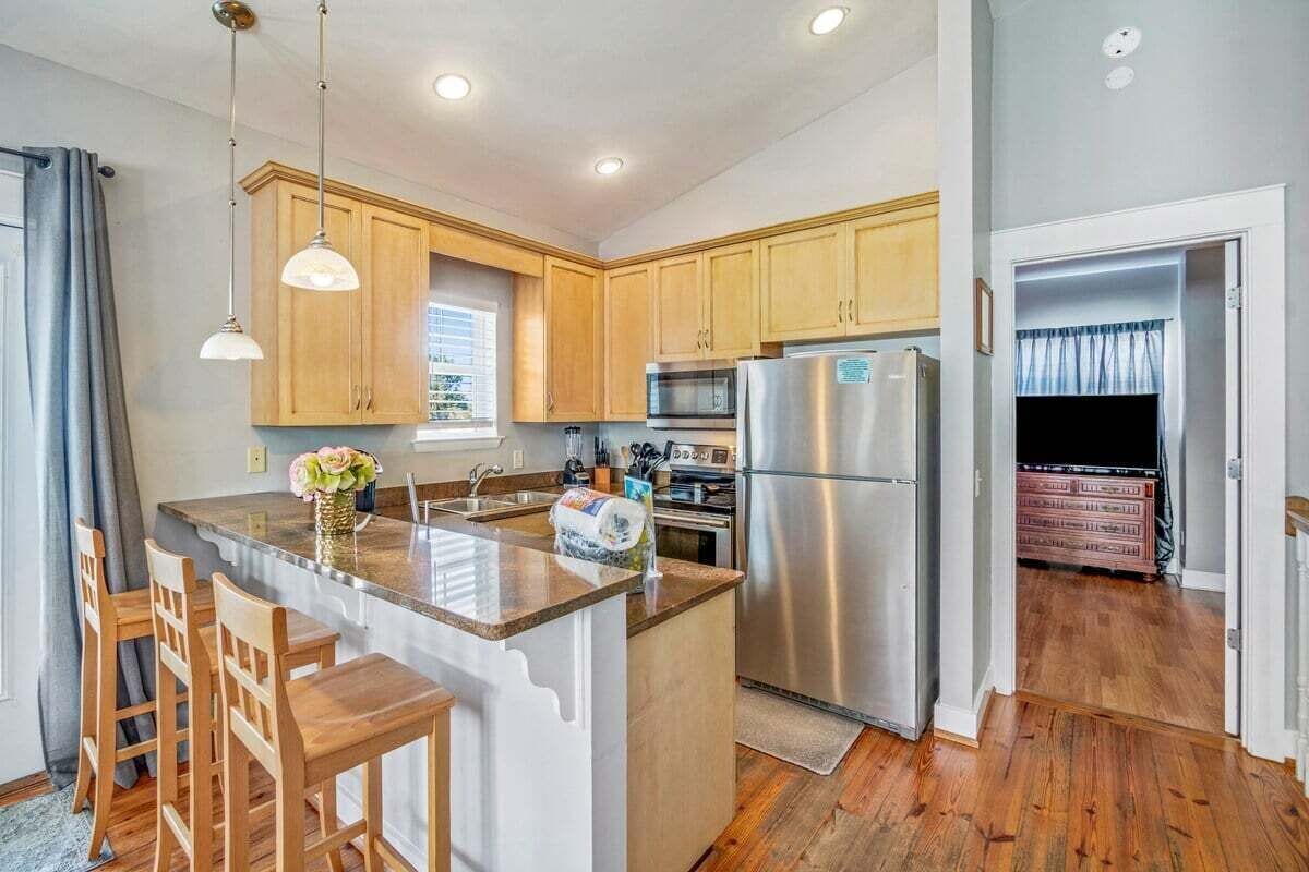 A modern kitchen with wooden cabinets, stainless steel appliances, and a central island with bar stools.