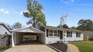 Une maison de plain-pied avec un garage fermé, une petite cour avant agrémentée d’un jardin et une clôture en bois.