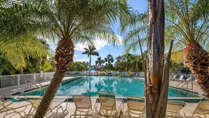 Une piscine avec des chaises longues et des palmiers.