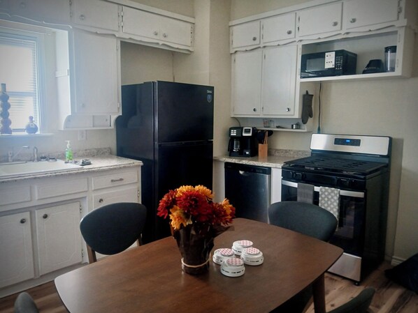 A compact kitchen with white cabinets, a black refrigerator, a coffee maker, and a stove. - The Wander Inn: 2 Bed-2 Bath Bungalow Recently Renovated, Walk to Downtown (Weatherford)