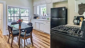 A kitchen with white cabinets, a black refrigerator, a gas stove, and a dining table with chairs.