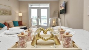 A dining area with a table set for two, featuring a decorative glass holder with a heart-shaped base.