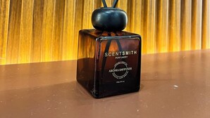 A ScentSmith aroma diffuser with four reeds, placed on a surface with a wooden background. - Affordable Transient Room in Lipa City Near SM and LIMA (Lipa City)
