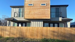 Una casa moderna de dos pisos con fachada y valla de madera.