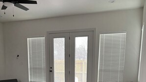 Un salón amplio con un sofá seccional gris, una mesita redonda y un ventilador de techo.