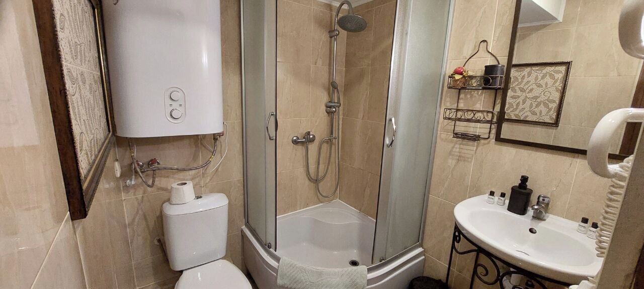 A bathroom with a toilet, a shower with a glass door, a sink, and a towel rack.