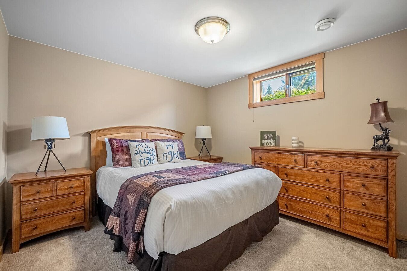 A bedroom with a bed, two nightstands, a dresser, and a window.