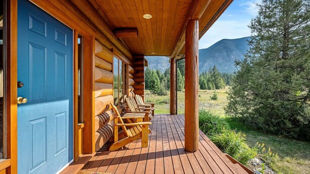 A log cabin with a blue door, wooden deck, and outdoor seating area with chairs.