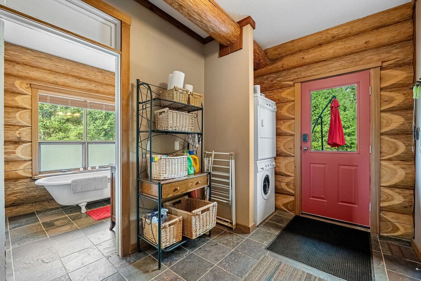 A laundry room with a white washing machine, a red door, and a wooden wall.