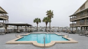 A rooftop pool with palm trees, lounge chairs, and a view of the city. - Two Suns at The Beach - White Sand and Shopping (Orange Beach)