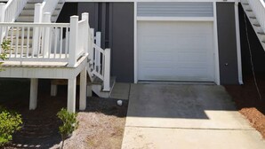 A multi-story residential building with a grey exterior, white railings, and a garage.