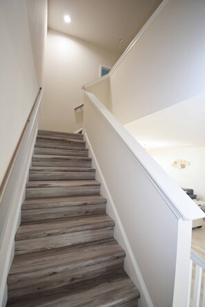 Una escalera con peldaños de madera y paredes blancas.