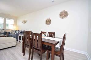 Un comedor con una mesa y sillas de madera, un sofá y decoración en la pared.