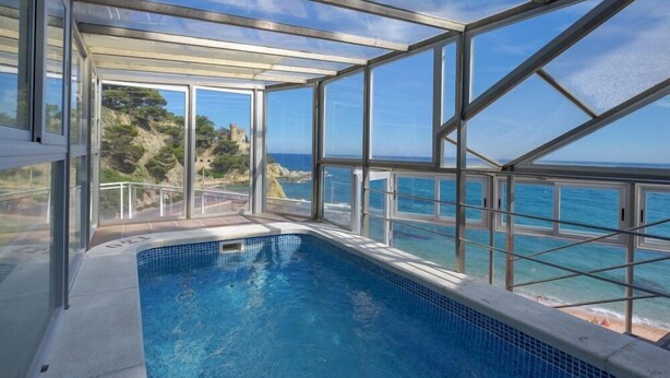 A glass-enclosed swimming pool with a clear view of the ocean and a distant castle. - Rosamar Maxim Adults Only (Lloret de Mar)