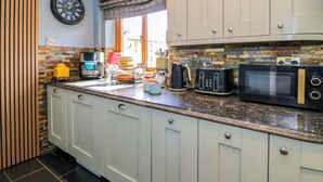 Cozinha com armários brancos, bancada de granito, cafeteira, torradeira e micro-ondas.