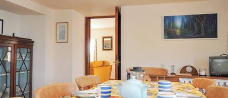A dining area with a table set for breakfast, including croissants and coffee cups.