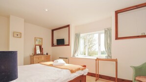 A bedroom with a bed, dresser, mirror, window, and chair. - Rosewin Farmhouse (Wadebridge)