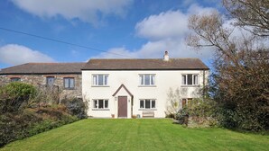 A two-story house with a front lawn, a wooden door, and a chimney. - Rosewin Farmhouse (Wadebridge)