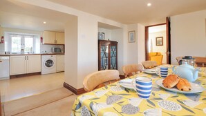 A well-lit kitchen with modern appliances, a dining area with a table set for two, and a cozy living space with a sofa and a coffee table. - Rosewin Farmhouse (Wadebridge)