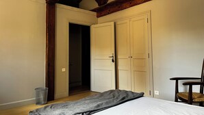 Un dormitorio con cama, una silla y un armario.