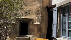 Un patio con paredes de piedra, una mesa pequeña, una silla y un paraguas amarillo.