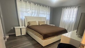 A bedroom with a bed, bedside tables, a trash bin, and a ceiling light.