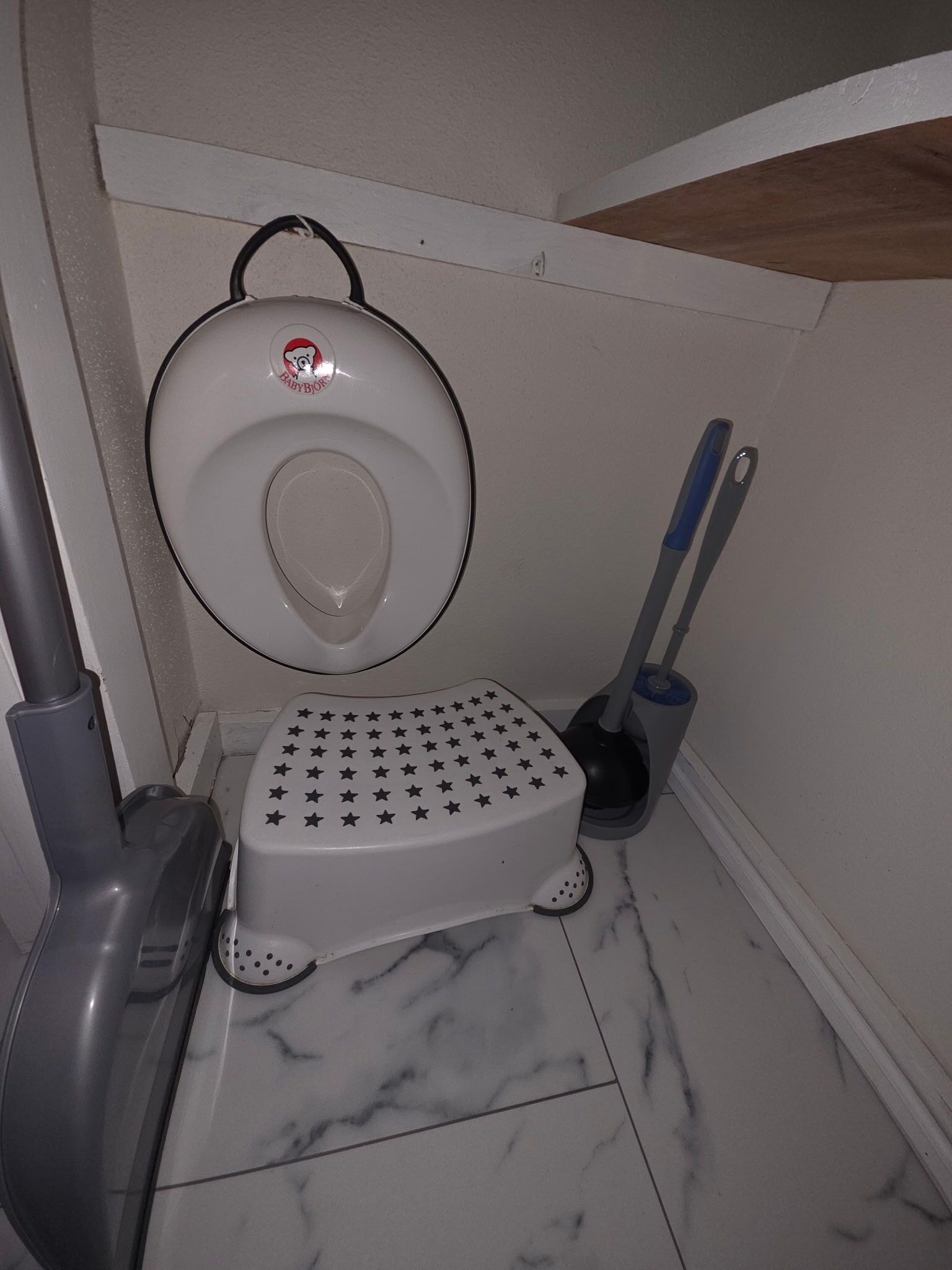Een kleine badkamer met een toilet, een hygiëneschuimer en een ontstoppingsveer.