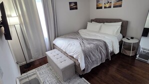 A bedroom with a bed, bedside table, and a small stool. - Welcome to The Hangar, a newly remodeled travel-themed stay, 4 minutes from BDL. (Windsor Locks)