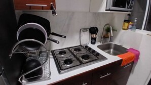 Une cuisine de taille réduite équipée d’une cuisinière, d’un four à micro-ondes et d’un évier.