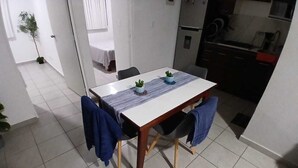 Un espace repas avec une table, des chaises et une cuisine en arrière-plan.