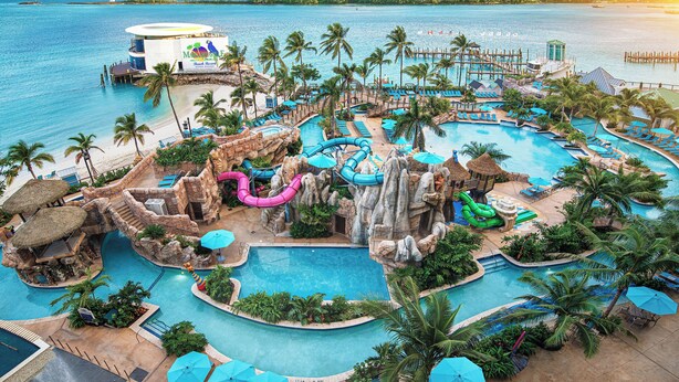 Ein Resort mit mehreren Schwimmbecken, Palmen und einer Strandanlage.