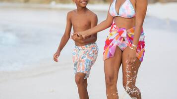 A beach scene with a person in a colorful swimsuit and another in swim trunks.