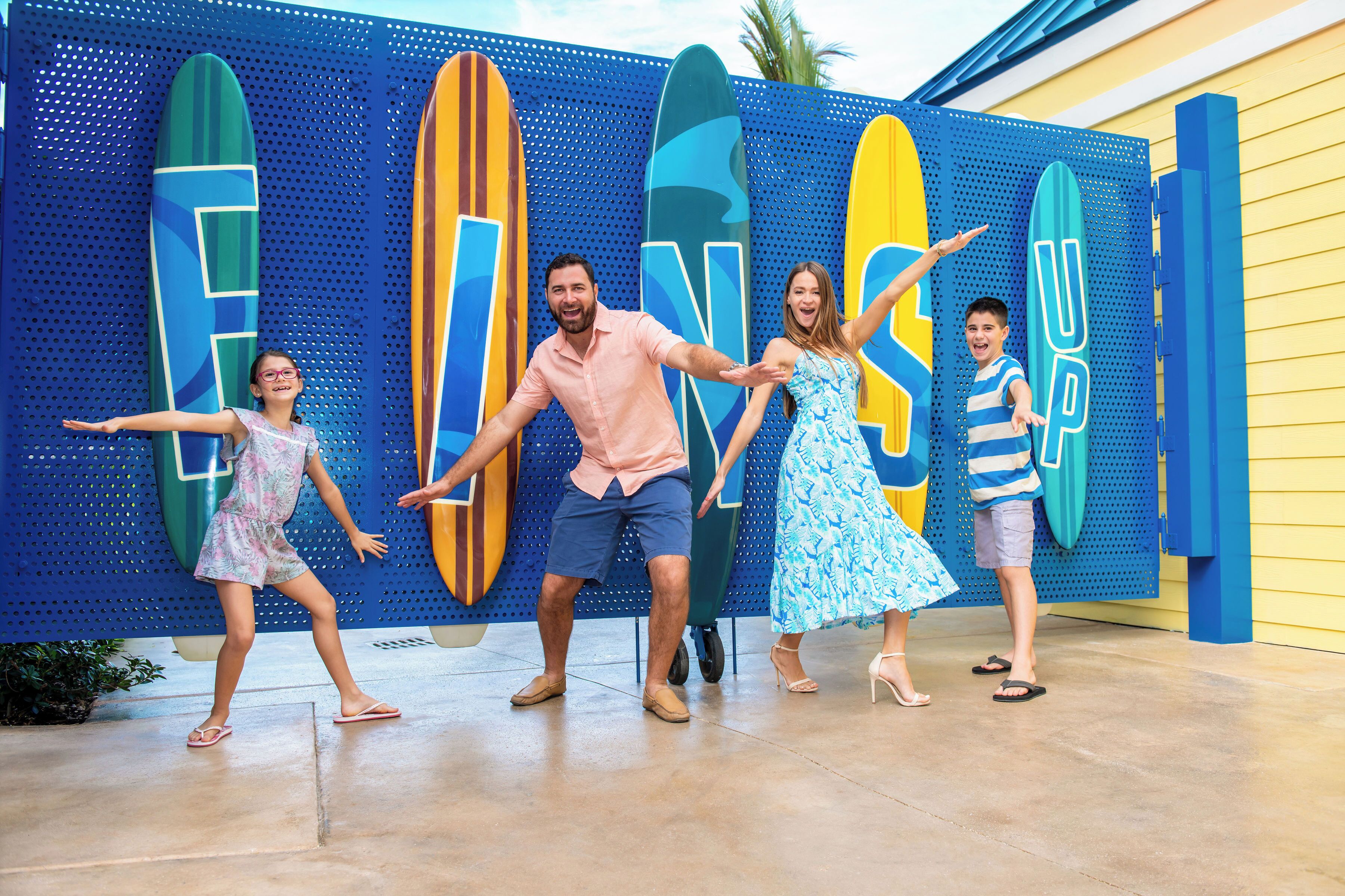 A family posing in front of a surfboard-themed backdrop.